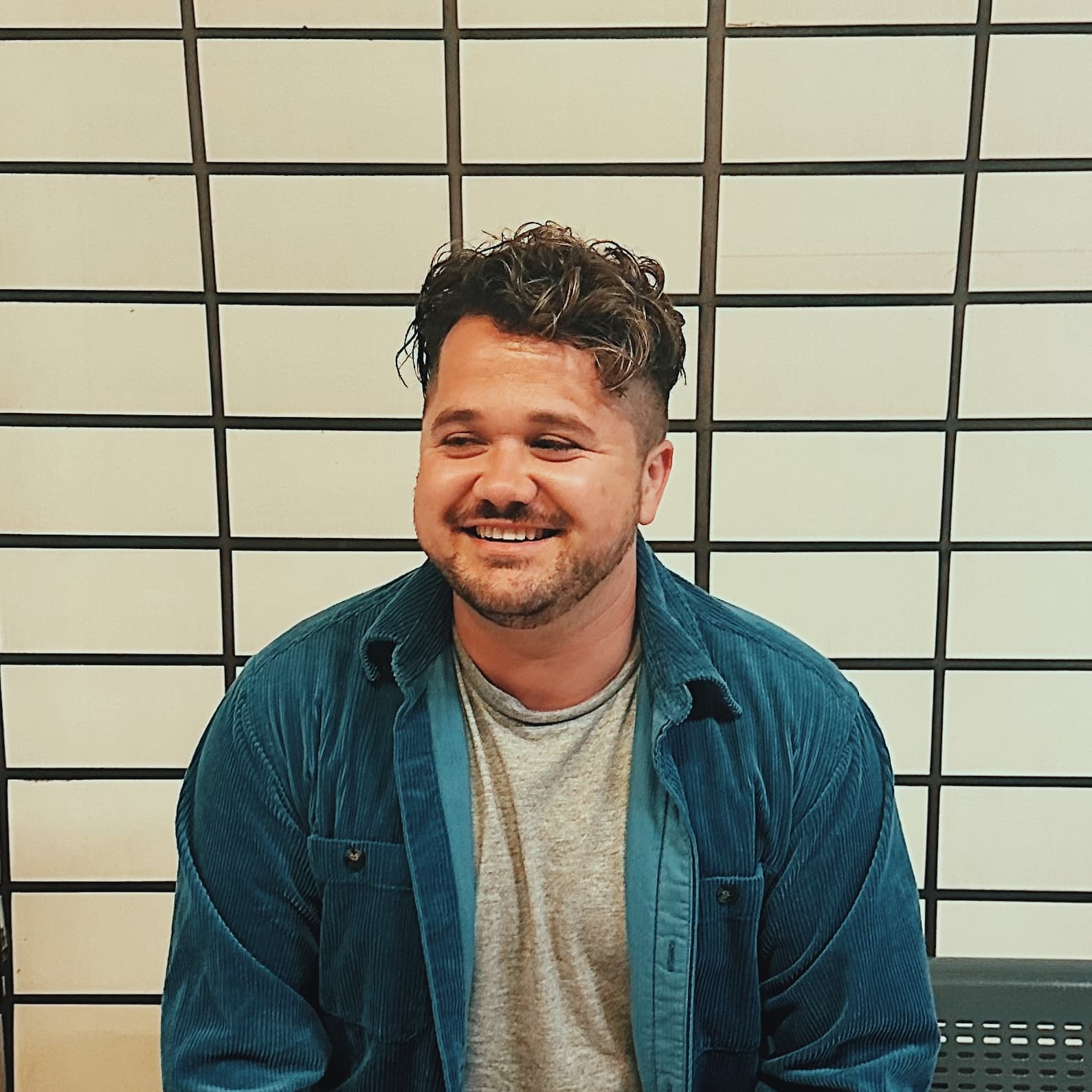 Laurence Grinyer smiling in front of a tiled wall